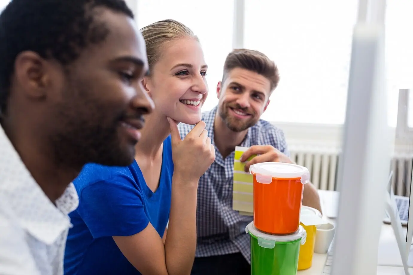 Gruppe von Grafikdesignern, die beim Arbeiten am Computer lächeln.