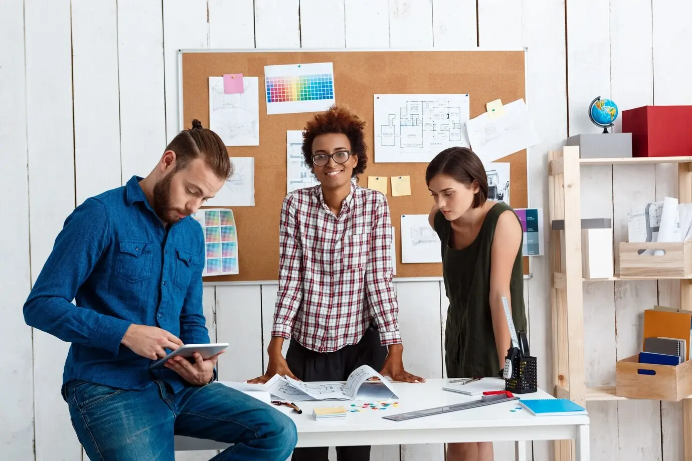 Kollegen lächeln, sprechen und diskutieren über Zeichnungen und neue Ideen